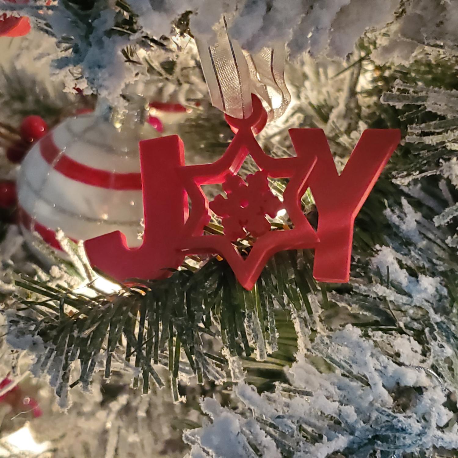 red 3d printed joy ornament in tree